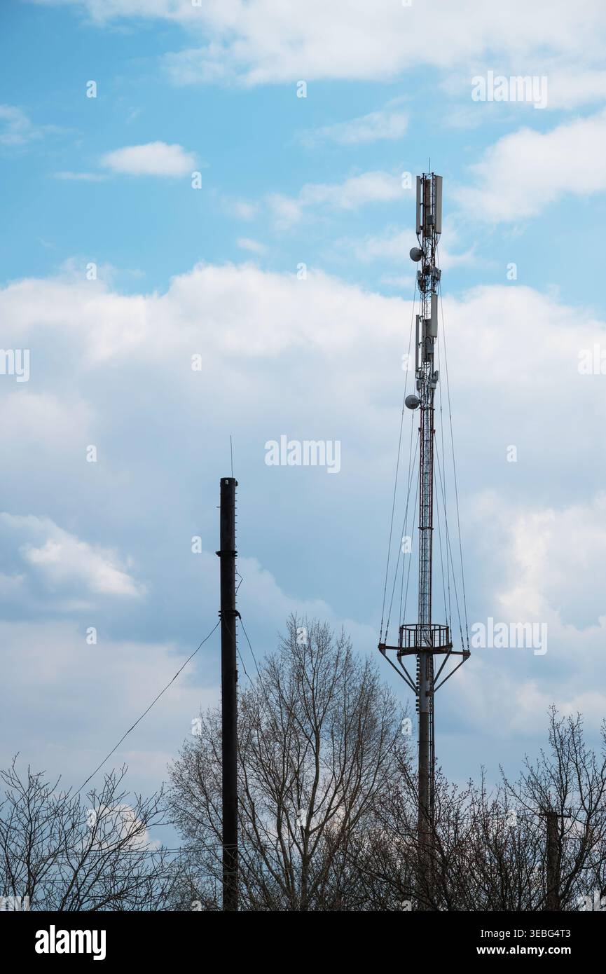 Torre di comunicazione mobile che si innalza sopra il cielo blu nuvoloso Foto Stock