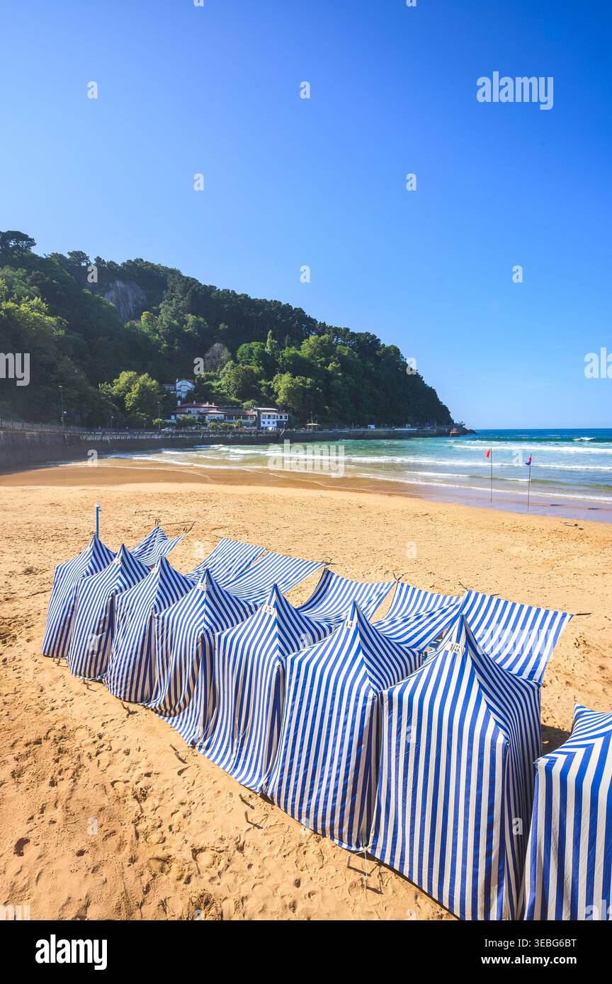 Tende da spiaggia tradizionali a righe blu e bianche sulla spiaggia sabbiosa in estate, Zarautz Beach, Zarautz, Paesi Baschi, Spagna Foto Stock