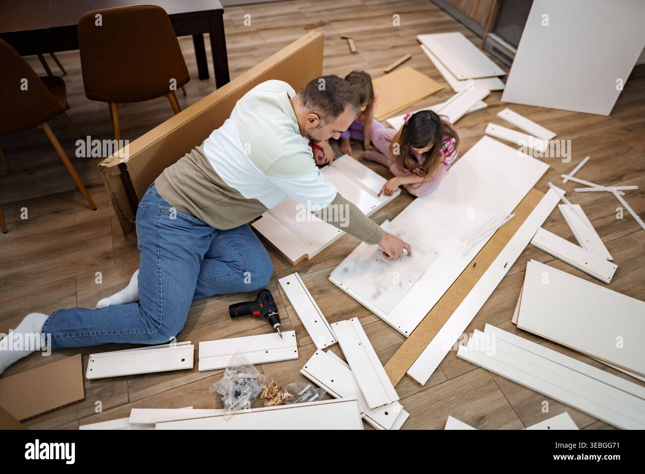 Legatura familiare durante l'assemblaggio di mobili nel weekend pomeridiano Foto Stock