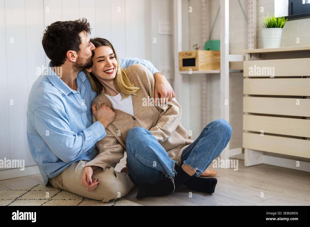 Coppia felice e variegata che condivide un momento di gioia a casa, abbracciando e sorridendo insieme Foto Stock