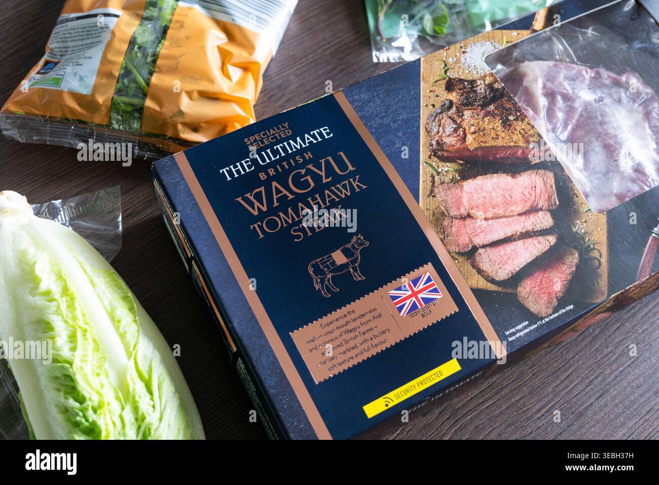 Confezione di bistecca Wagyu Tomahawk britannica con ingredienti da cucina adiacente, Regno Unito. Concetto: Carne costosa, furto di cibo, costo della vita, taglio di bistecche di manzo Foto Stock