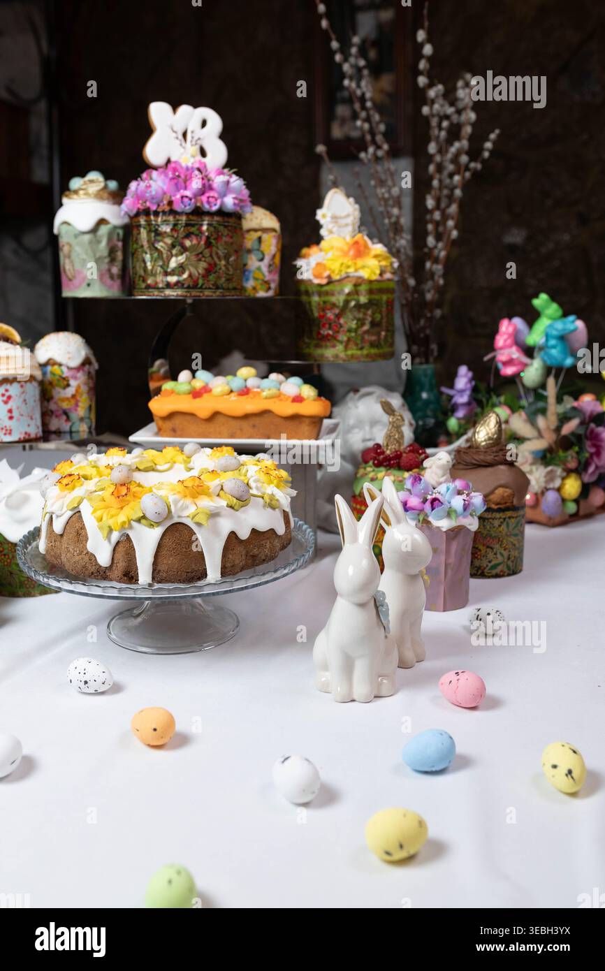 Varietà di torte pasquali ornate con ricche decorazioni floreali su uno stand a più piani. Foto Stock