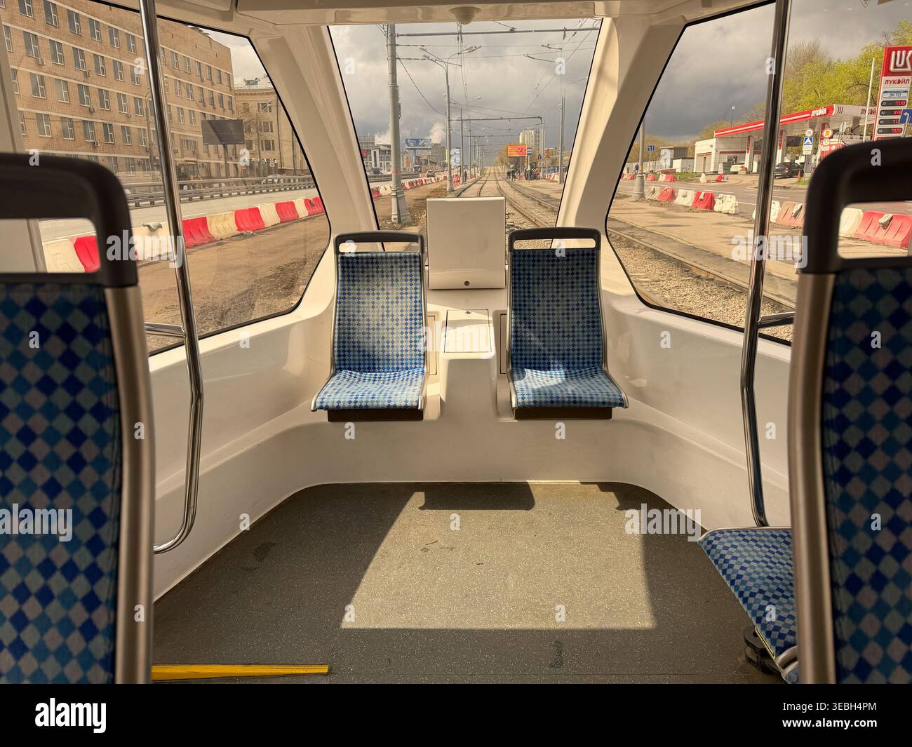 Mosca, Russia - 26 aprile 2026: Vista interna anteriore della moderna cabina del tram con sedili e strada di costruzione della città visibile attraverso la finestra. La vita urbana doc Foto Stock
