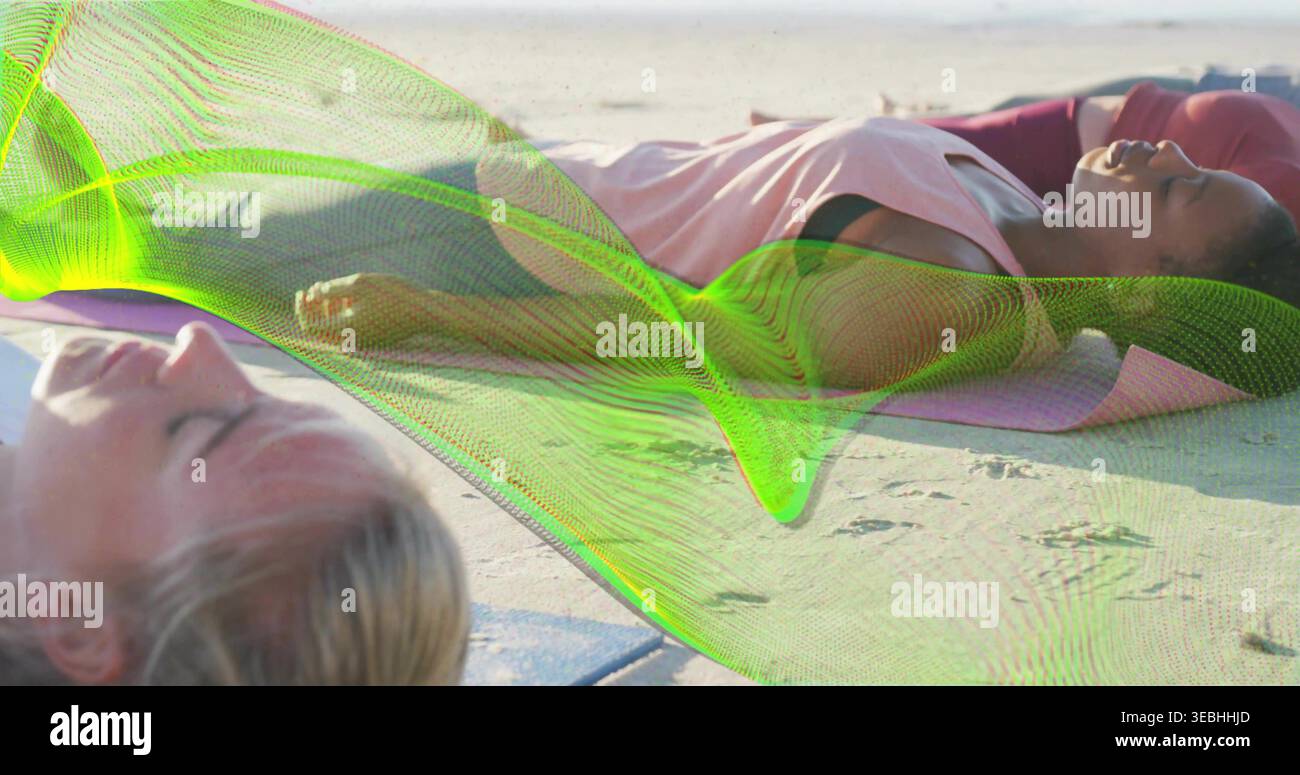 Donne sdraiate che riposano sulla spiaggia sabbiosa, indossano top rosa pastello, tappetini yoga viola, rivestimento verde neon Foto Stock