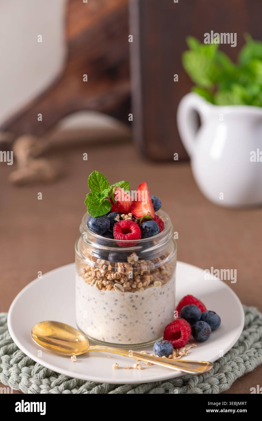 Nutriente parfait per la colazione con strati di budino di chia cremoso e granola croccante. Guarnite con fragole e mirtilli in morbido naturale Foto Stock