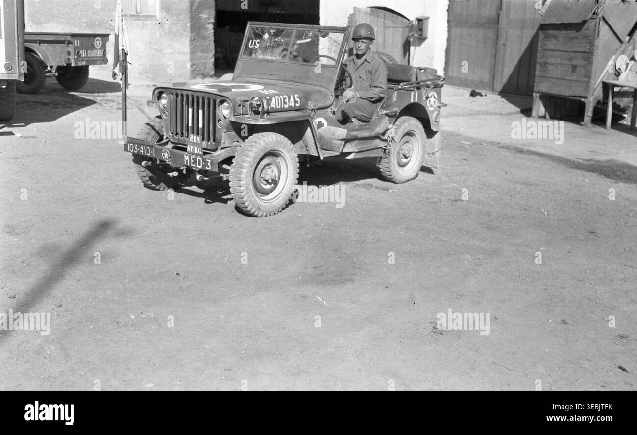 Vista angolata di una Jeep medica dell'esercito degli Stati Uniti dal 410th Infantry Regiment della 103rd Infantry Division, contrassegnata per la sezione chirurgica del 2nd Battalion, fotografata accanto a un edificio in quella che è probabilmente l'Alsazia, Francia, tra la fine del 1944 e l'inizio del 1945. Foto Stock