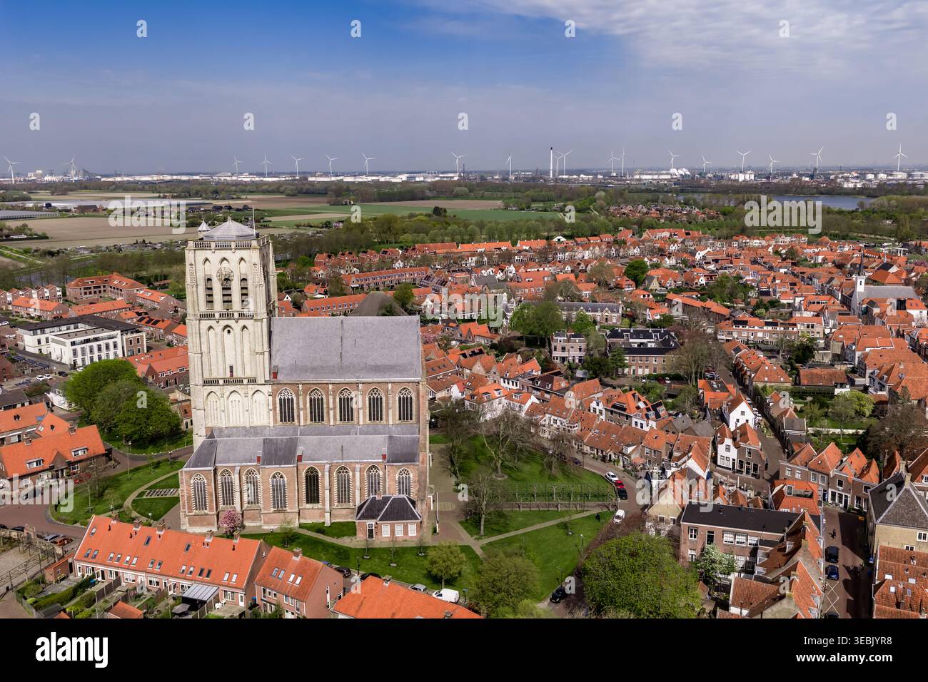 Veduta laterale aerea della Brielle Gothic Church Tower con turbine eoliche e industria portuale su Horizon Netherlands Foto Stock