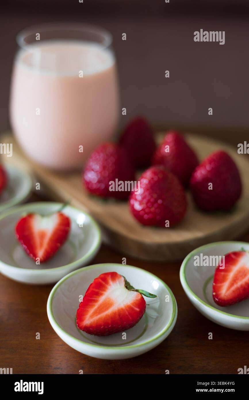 Un primo piano di frutta matura di fragole servite con un bicchiere di latte di fragole su un tavolo di legno. Vista dall'alto. Posizione piatta. Foto Stock