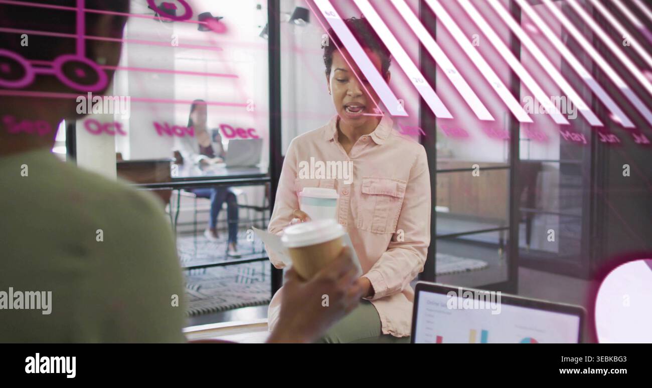 Una donna con una camicia rosa che prende il caffè in ufficio, carte per laptop, decalcomanie rosa Foto Stock