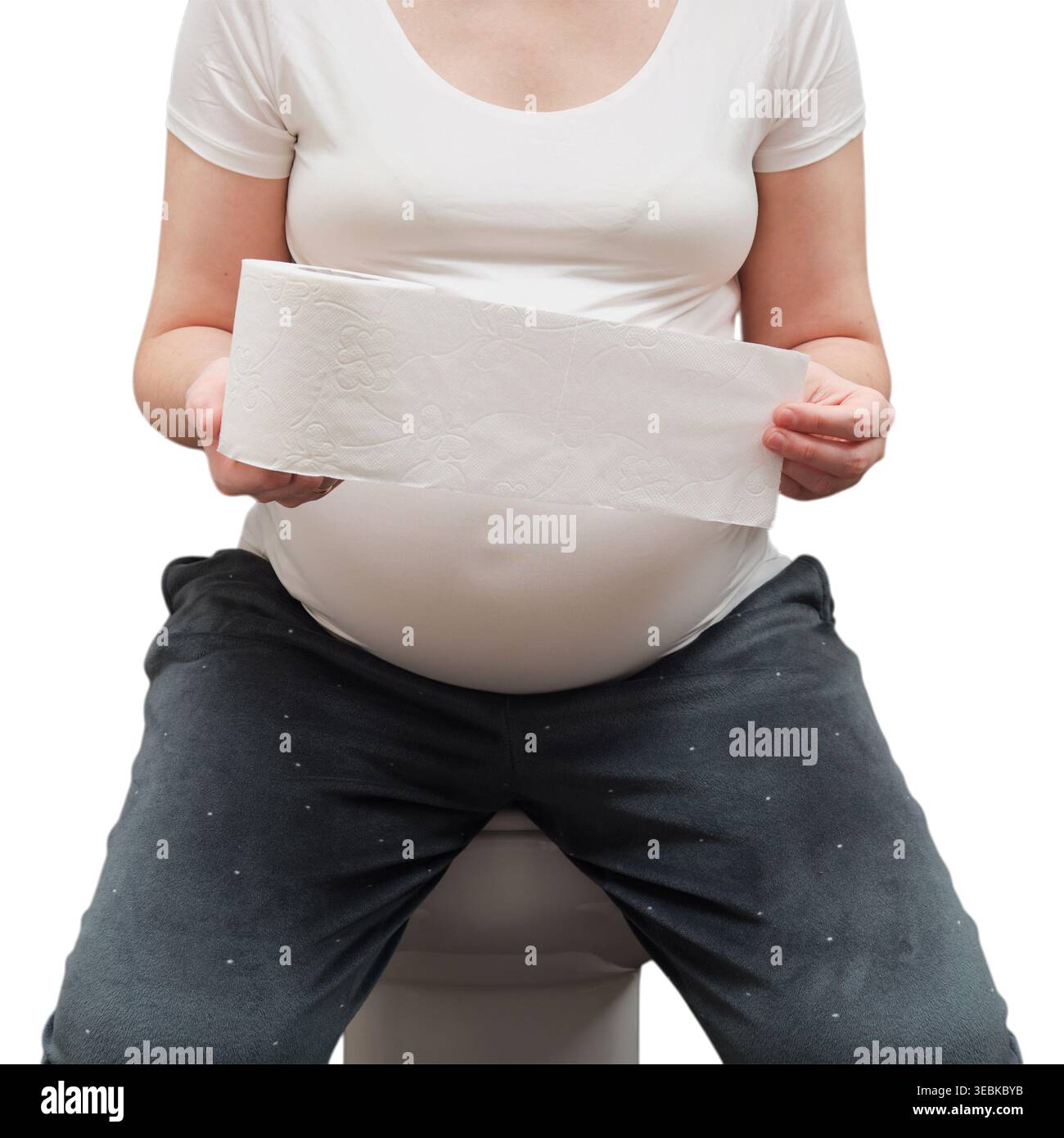Donna incinta seduta sul water che regge un rotolo di carta. La madre incinta si prende cura dell'igiene del corpo durante il periodo di gestazione. Concetto di salute e benessere Foto Stock