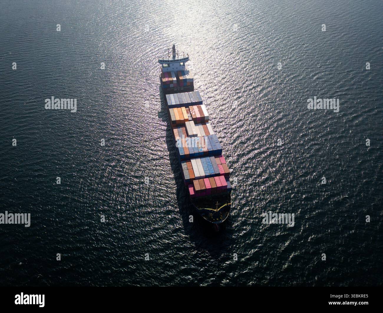 Veduta aerea di una grande nave portacontainer che naviga nell'oceano, forte bagliore del sole Foto Stock