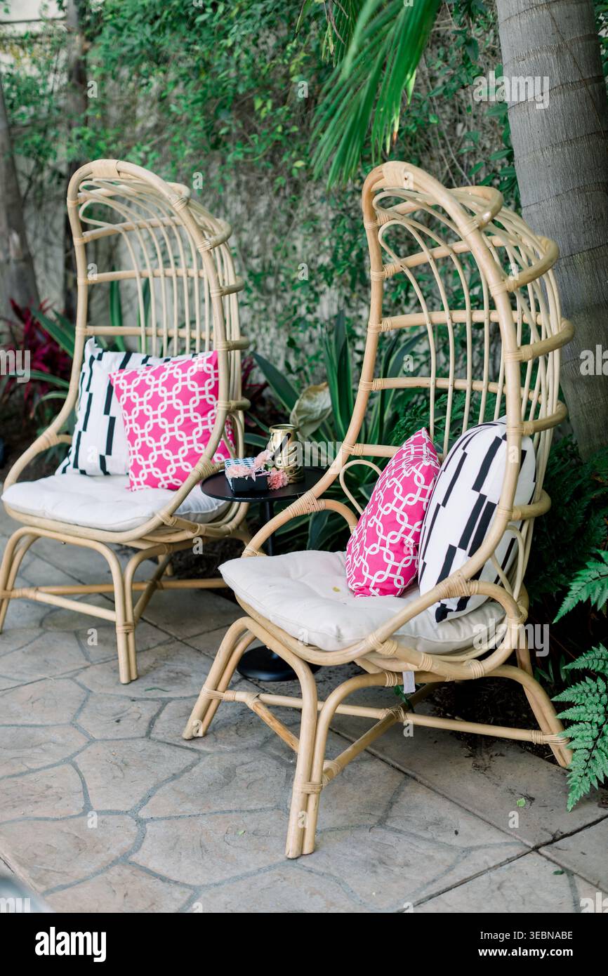 Elegante patio esterno con sedie a pavone in rattan e cuscini rosa Foto Stock