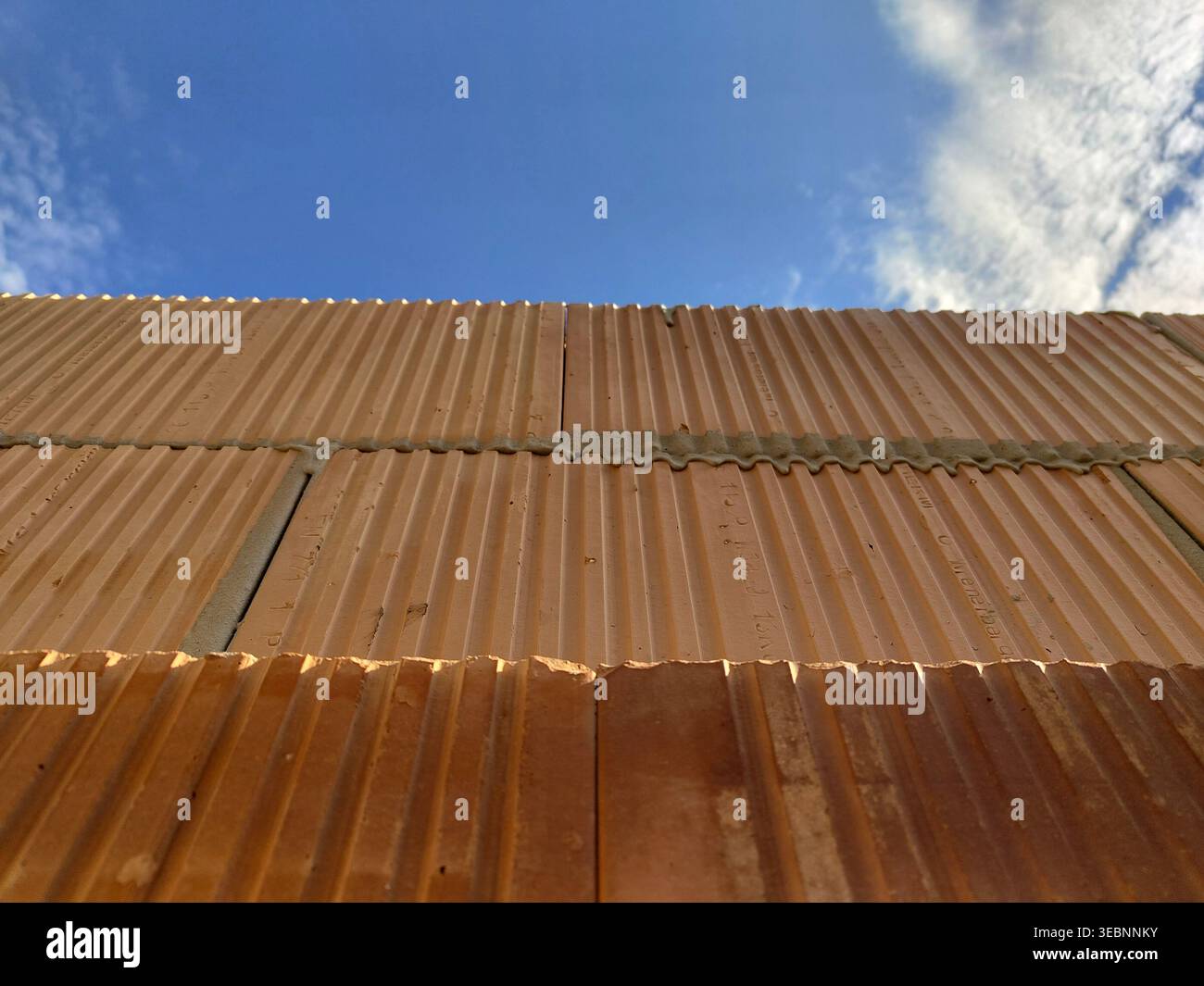 Vista ravvicinata dei blocchi di argilla con scanalature e giunti di Malta che formano la struttura delle pareti sullo sfondo del cielo. Costruzione, muratura, costruzione m Foto Stock