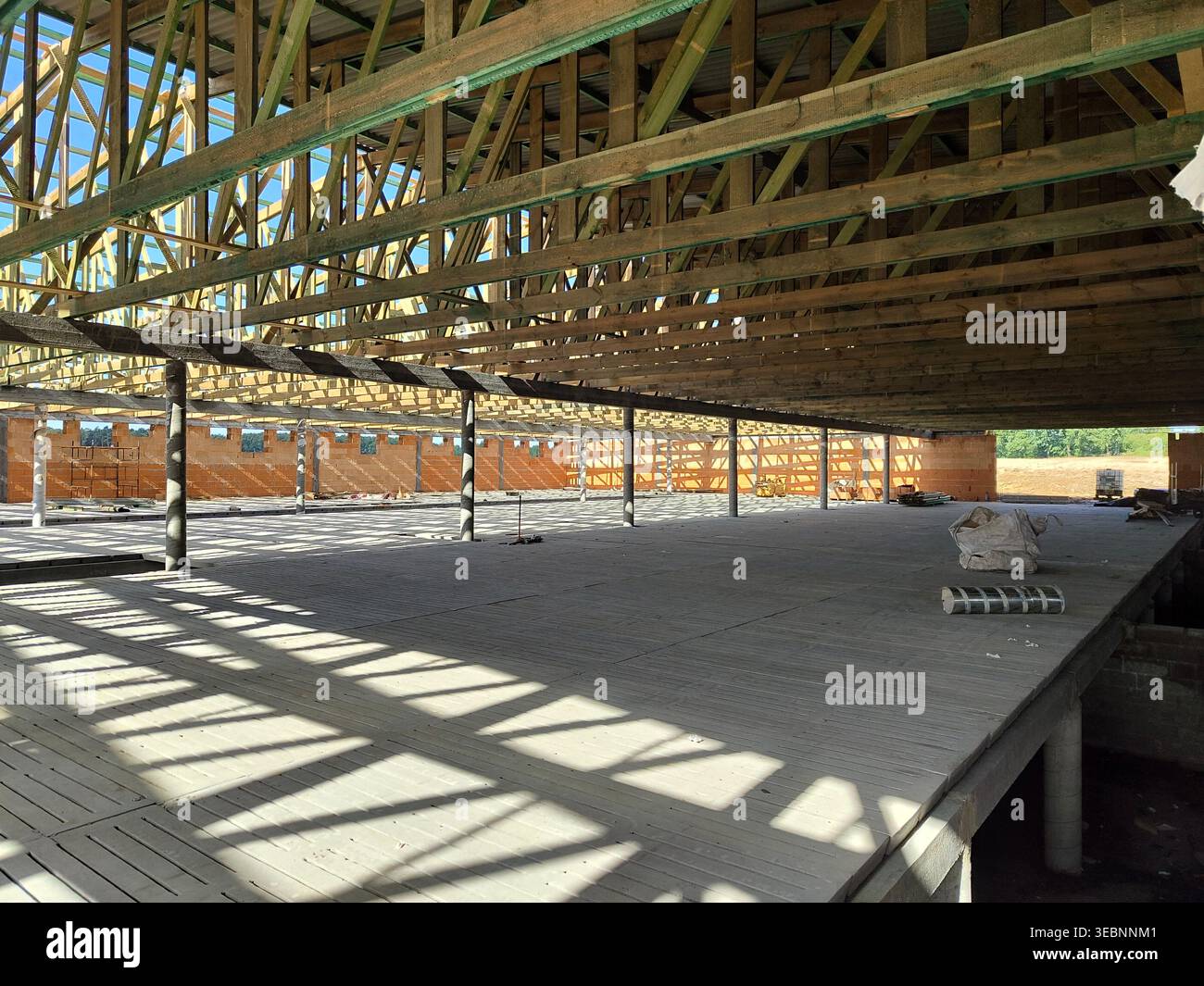 Ampia visuale del sistema di travi a capriate in legno installato sul grande pavimento dell'edificio con ombre e supporti strutturali. Edilizia, carpenteria, architettura, Foto Stock