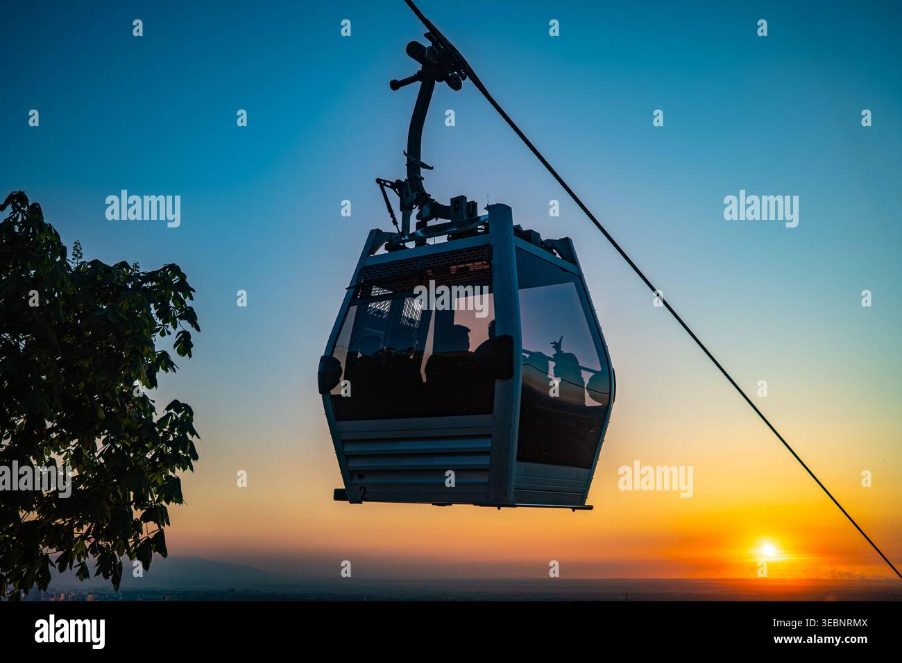 Sagoma della funivia sullo sfondo del suggestivo tramonto arancione con sole all'orizzonte Foto Stock