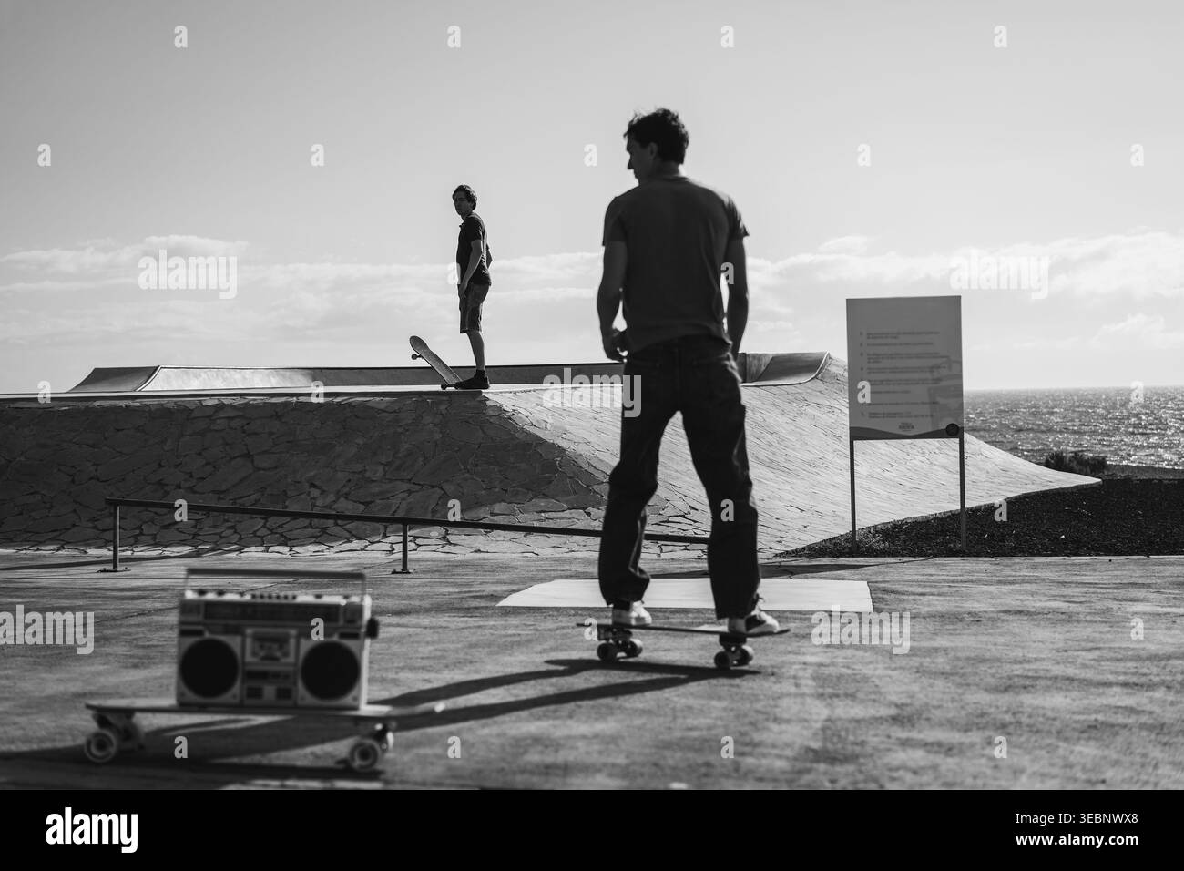Giovani che si divertono allo skateboard Park all'aperto - stile di vita estivo e concetto di sport estremi - attenzione principale sul corpo dell'uomo sinistro - bianco e nero Foto Stock