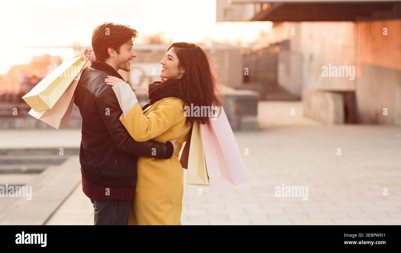 Coppia che ama fare shopping insieme nella vivace città al tramonto Foto Stock