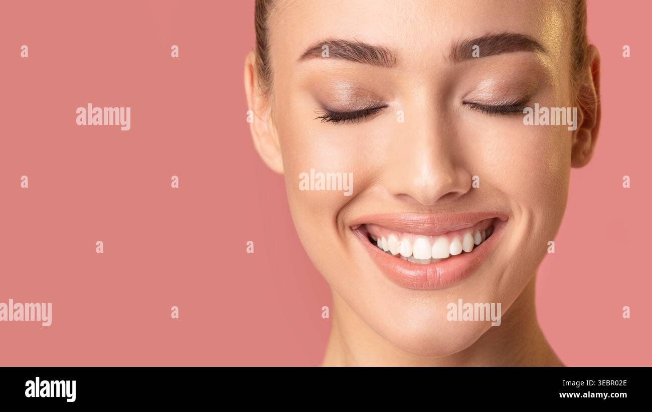Donna sorridente a occhi chiusi e pelle luminosa su sfondo rosa Foto Stock