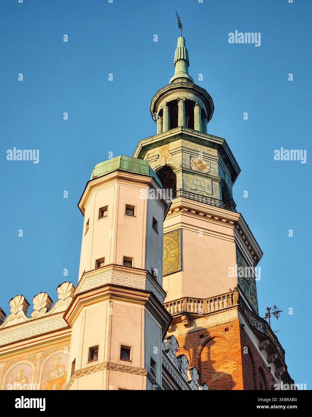 Torre del municipio a Poznań sotto i raggi del sole mattutino. Un primo piano della torre del municipio di Poznań con cupola verde in rame e torrette bianche ornate. Foto Stock