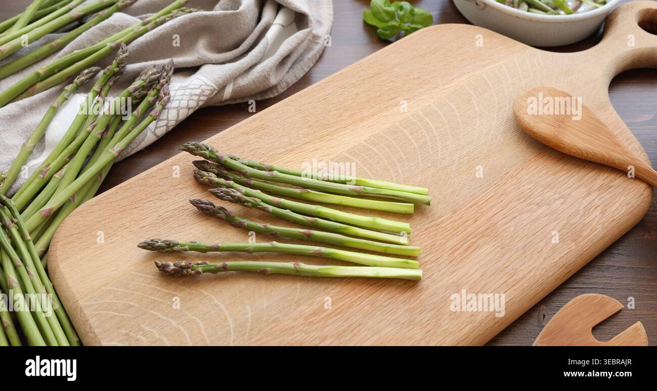 Lancia di asparagi verdi freschi su tavola in legno rustico. La cucina minimalista mette in risalto le verdure biologiche naturali per una sana cucina mediterranea Foto Stock