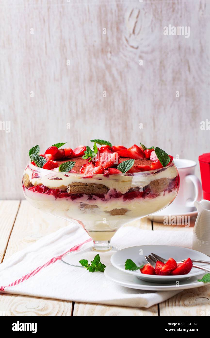 Dessert trifle alla fragola con strati di crema e menta in ciotola di vetro Foto Stock