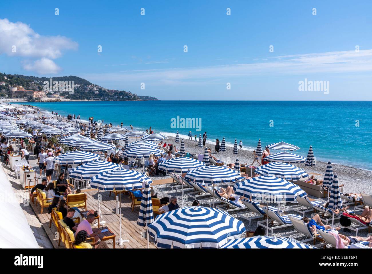 Francia, Nizza, ristorante sulla spiaggia con ombrelloni a righe blu e bianche. Foto Stock