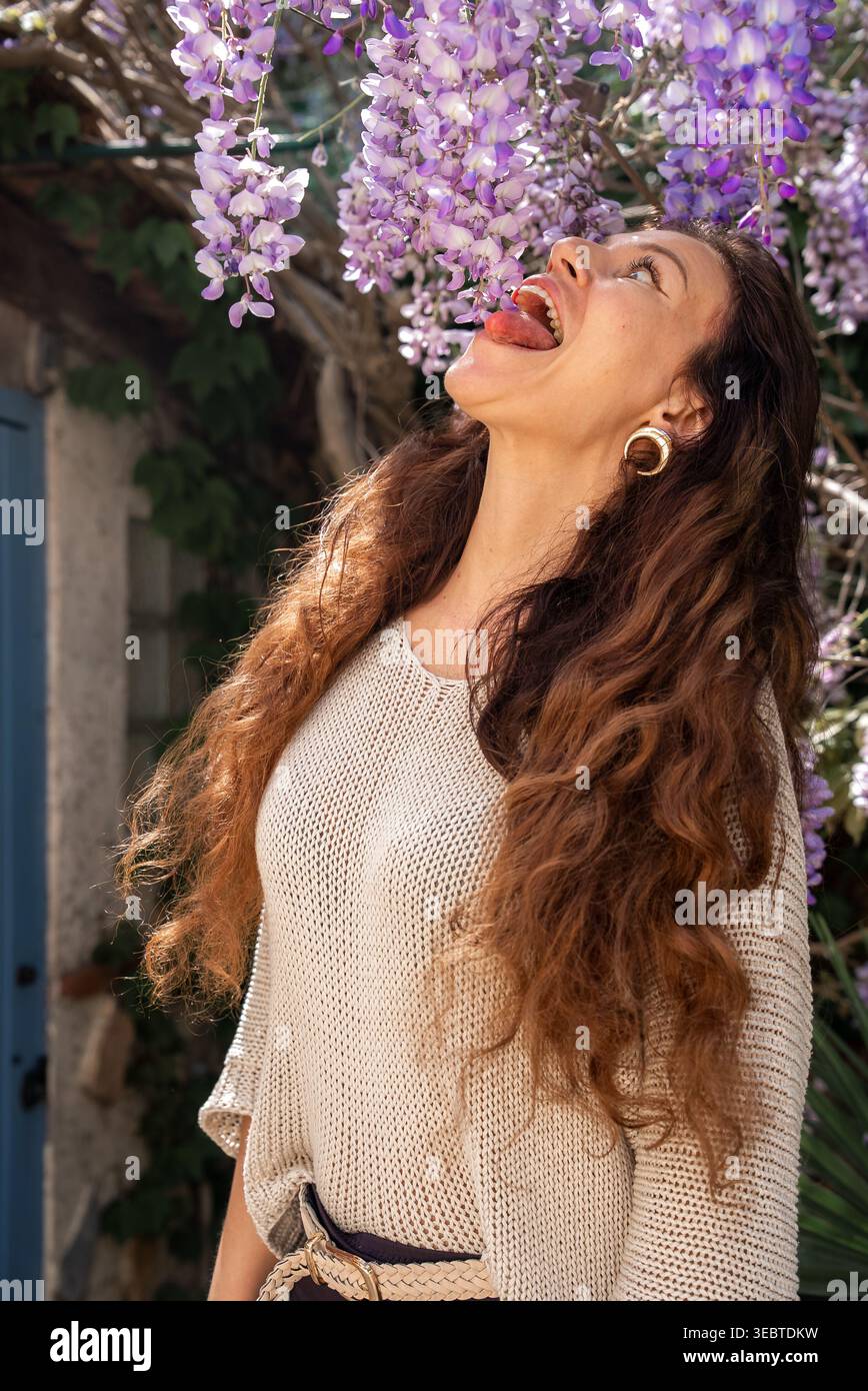 La donna gioca con la glicine nel cortile di Antibes con la porta blu Foto Stock