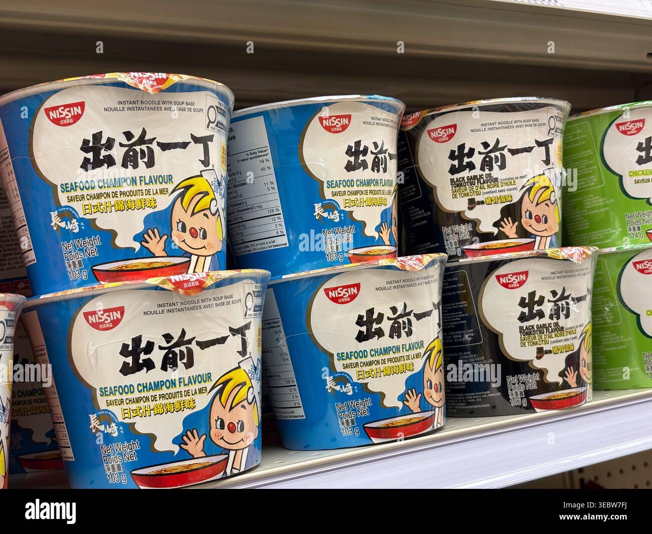 I gusti assortiti di spaghetti istantanei Nissin Demae Iccho sono esposti sullo scaffale di un negozio di alimentari, con vari marchi e dettagli di imballaggio. Foto Stock