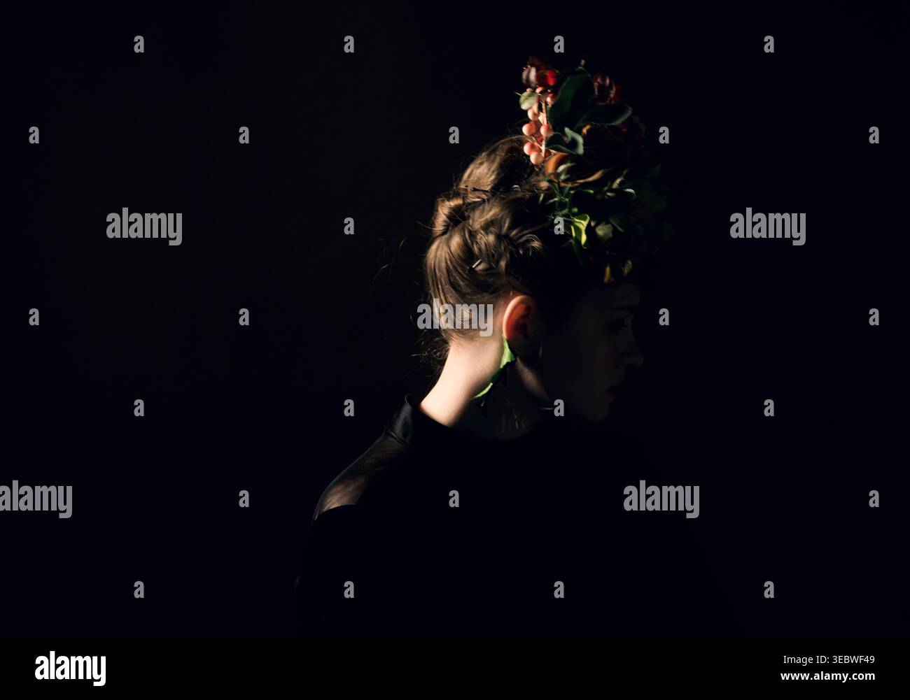 Elegante ritratto del profilo da donna che mostra un intreccio intrecciato con una splendida corona di fiori e foglie Foto Stock