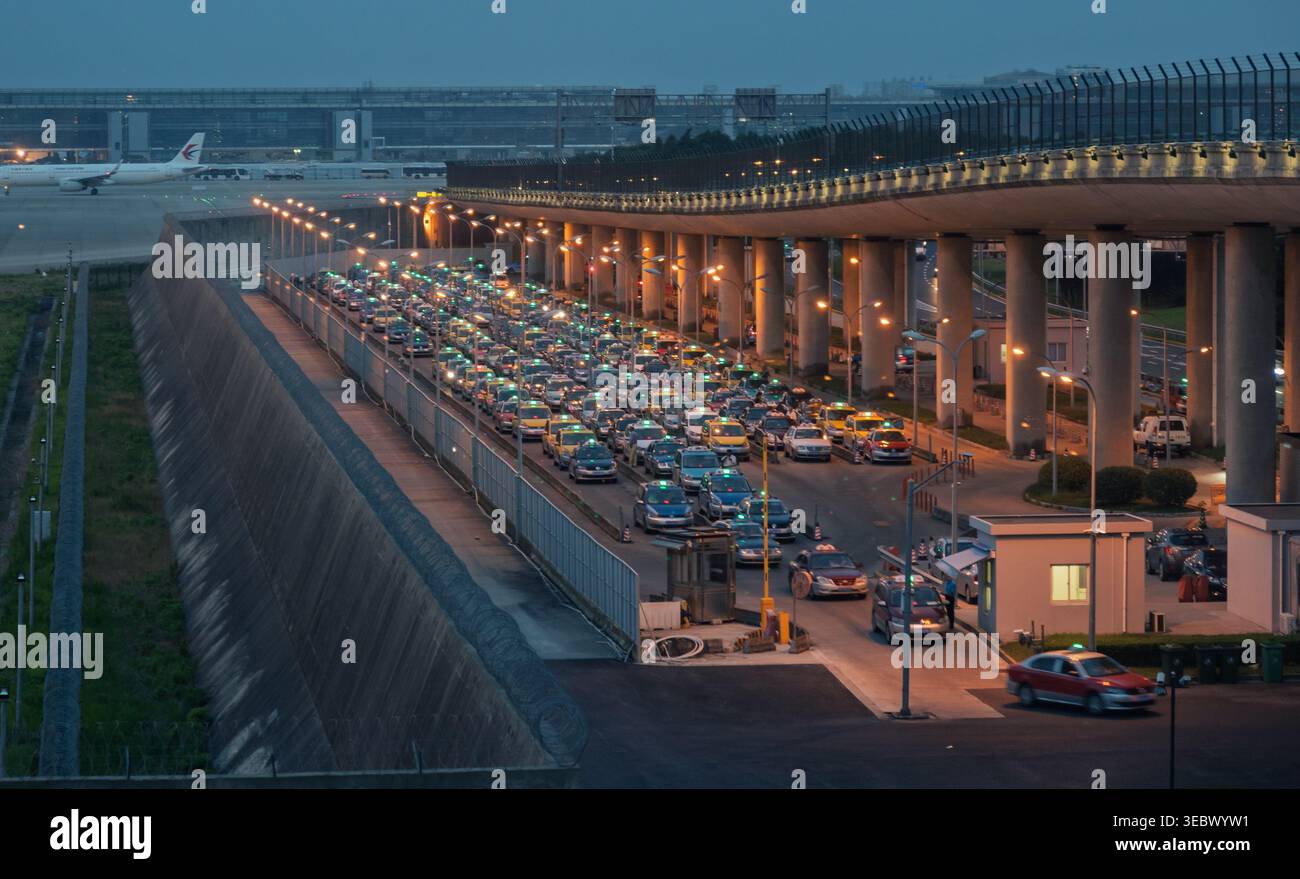 Shanghai, Cina - 2 luglio 2018: Numerosi taxi attendono in coda in un affollato aeroporto internazionale durante il crepuscolo serale. Foto Stock