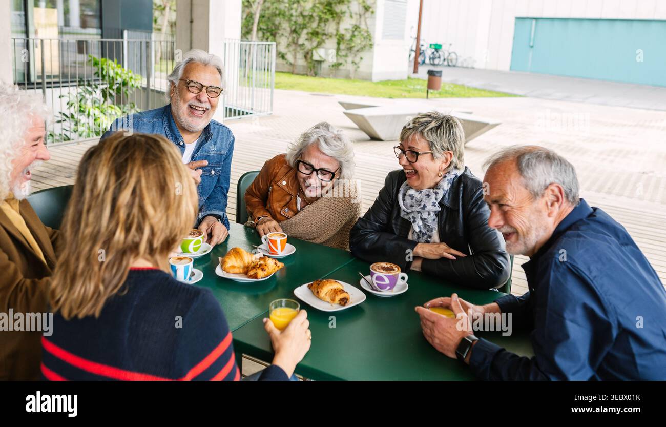 Amici anziani felici che sorridono durante la colazione al bar Foto Stock