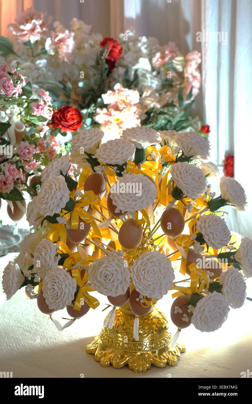 Intricata disposizione floreale di bunga pahar su piedistallo dorato con fiori e nastri colorati, simboleggiano le benedizioni e la prosperità del matrimonio malese c Foto Stock