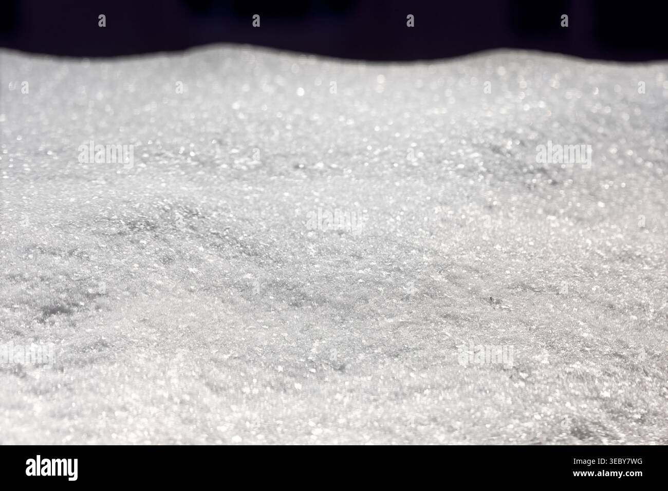 L'immacolata coperta di neve fresca si estende lungo la cornice, la sua superficie cristallina risplende con innumerevoli piccoli scintilli Foto Stock