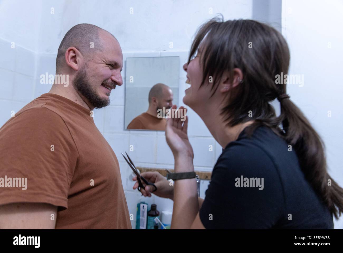 Una coppia felice che condivide una risata in un bagno modesto Foto Stock