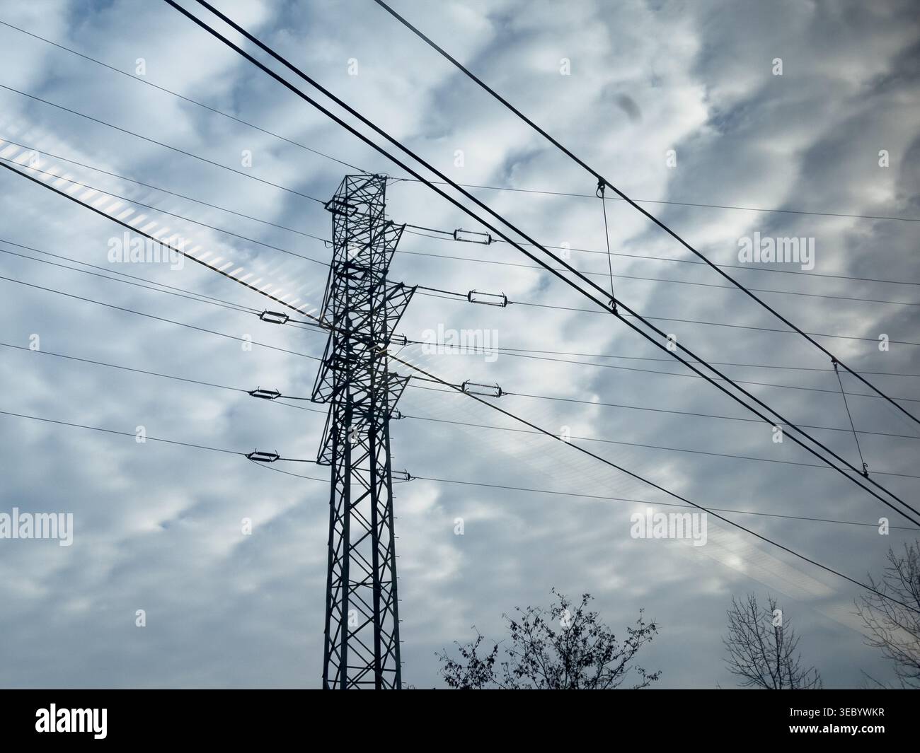 Un potente traliccio in acciaio trasporta linee elettriche aeree contro un cielo spettacolare pieno di nuvole testurizzate, che rappresentano la distribuzione dell'energia e la mia Foto Stock