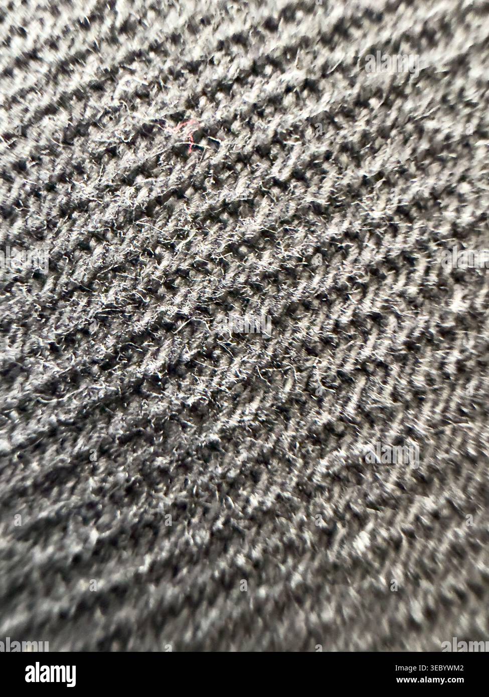 La macro fotografia cattura la trama dettagliata del materiale tessile grigio scuro con fili singoli e fibre morbide visibili, trasmettendo calore e testo Foto Stock