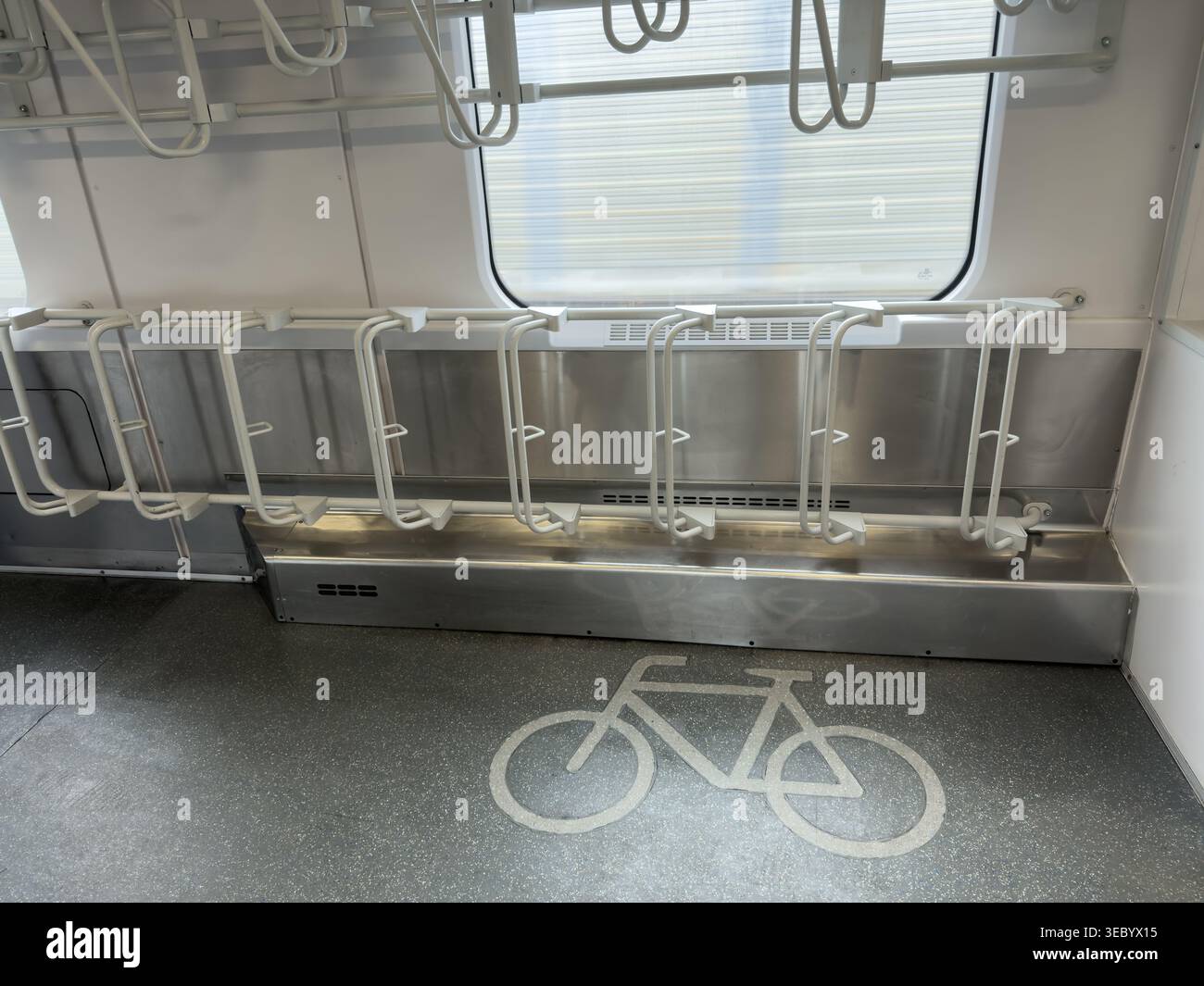 Un vano treno vuoto è dotato di portabiciclette speciali montate sulla parete e di un simbolo di pavimento trasparente che indica lo spazio dedicato ai ciclisti Foto Stock