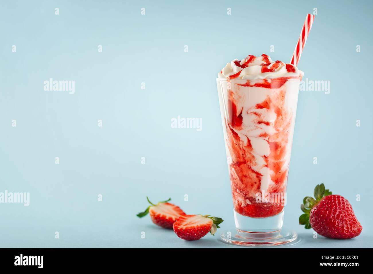 Frullato di fragole con panna montata e sciroppo di bacche nel bicchiere alto su sfondo blu. Foto Stock