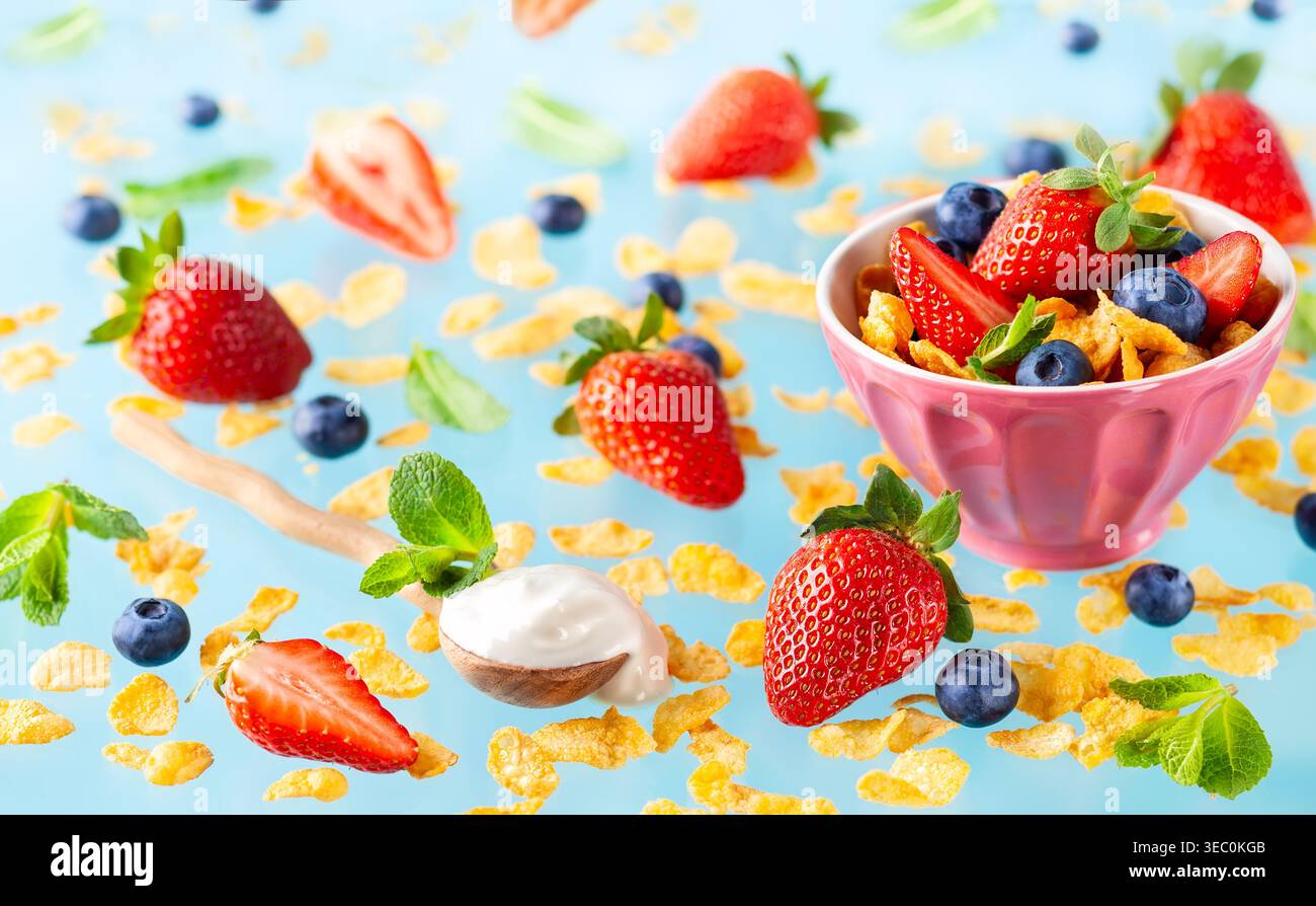 Concetto di sana colazione senza glutine con frutti di bosco, yogurt naturale e corn flakes su sfondo blu. Foto Stock