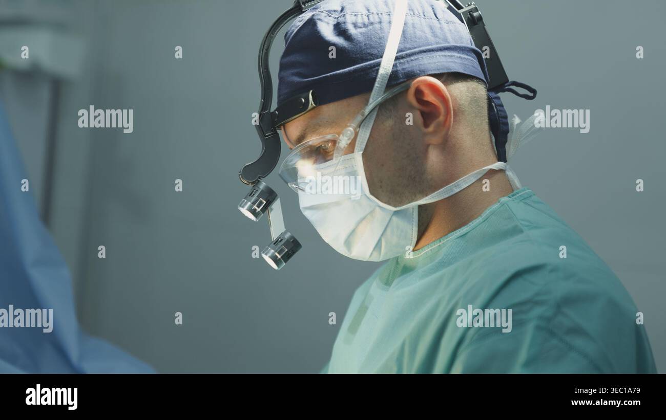 Primo piano chirurgo maschile in maschera medica protettiva medico uomo che indossa avanzate innovative loupes di chirurgia illuminazione lavoro medico clinica operatoria Foto Stock