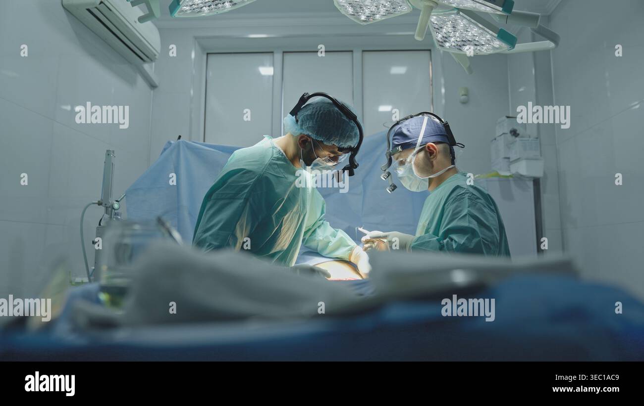 Squadra due medici medici medici chirurghi uomini che operano ginecologia cardiologia gastrica neurochirurgia ambulanza di emergenza aiutare cooperare chirurgia Foto Stock