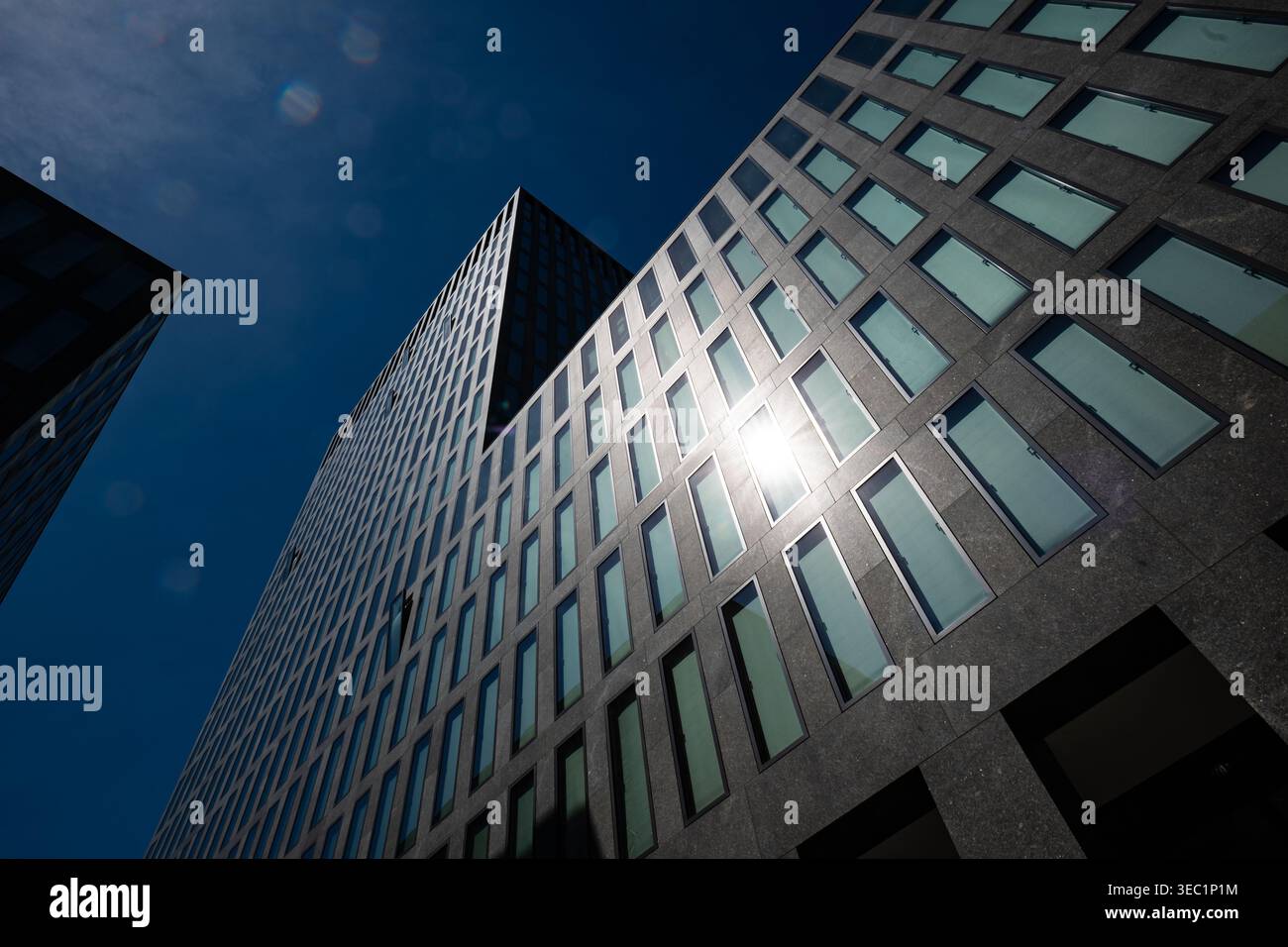 Riprese ad angolo basso con elevato contrasto tra materiali da costruzione scuri e luce solare brillante. Una singola finestra aperta interrompe la patch geometrica Foto Stock
