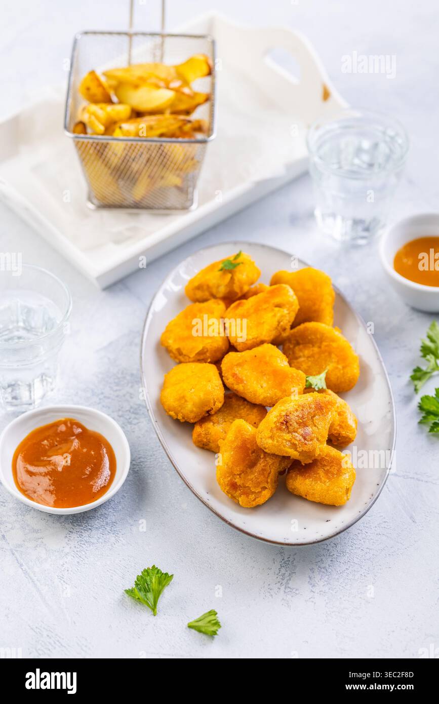 Pepite di pollo con patate fatte in casa e salse Foto Stock