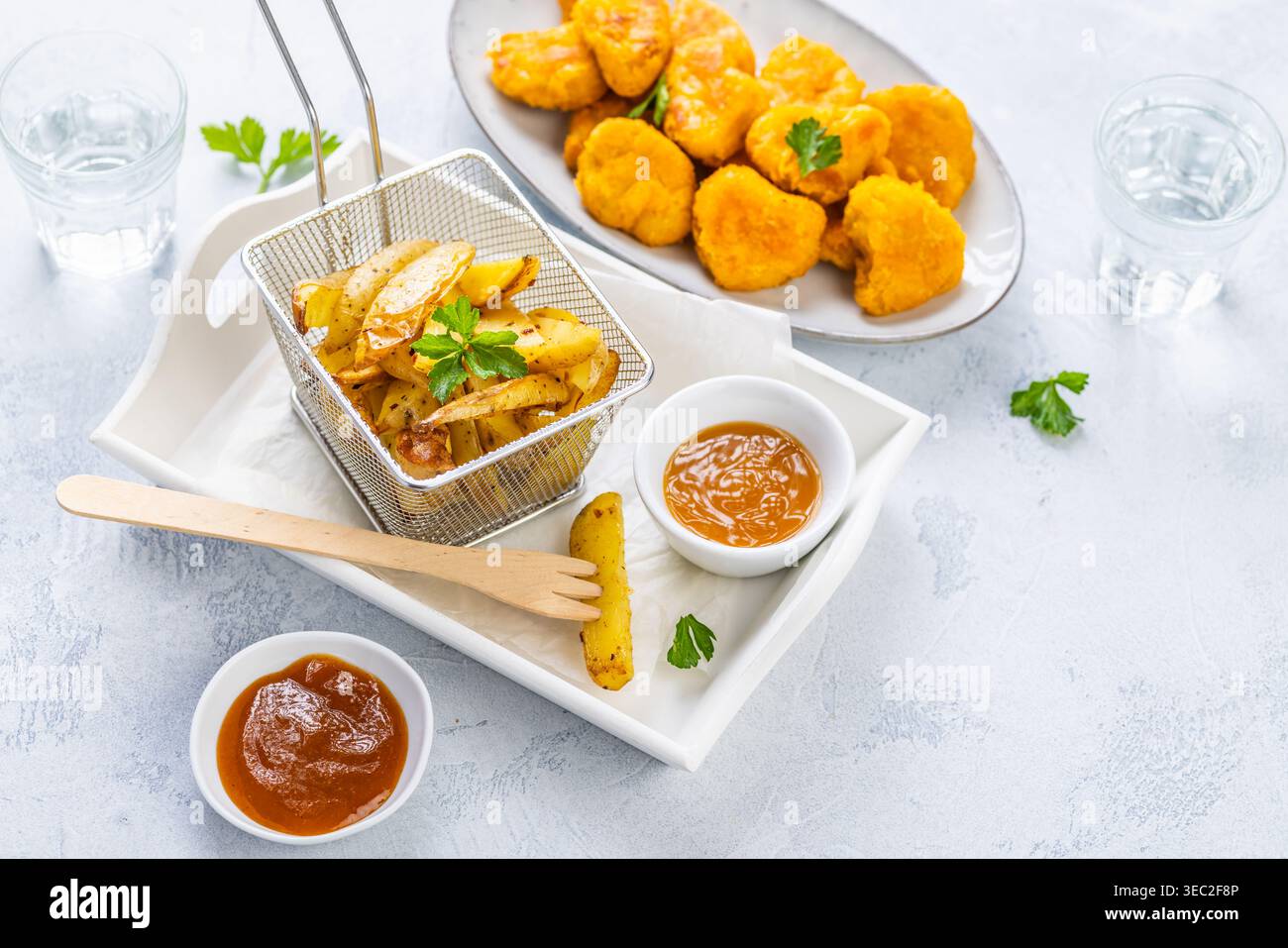 Pepite di pollo con patate fatte in casa e salse Foto Stock