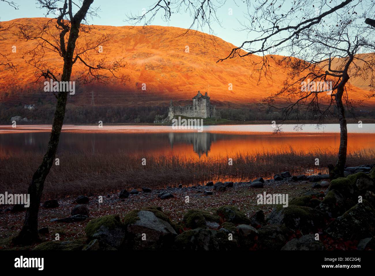 Rovine scozzesi di un antico castello in una mattina d'autunno. Colori autunnali sulle colline illuminate dal sole del mattino alle spalle. Loch Awe, Argyll e Bute, Scozia, Regno Unito Foto Stock