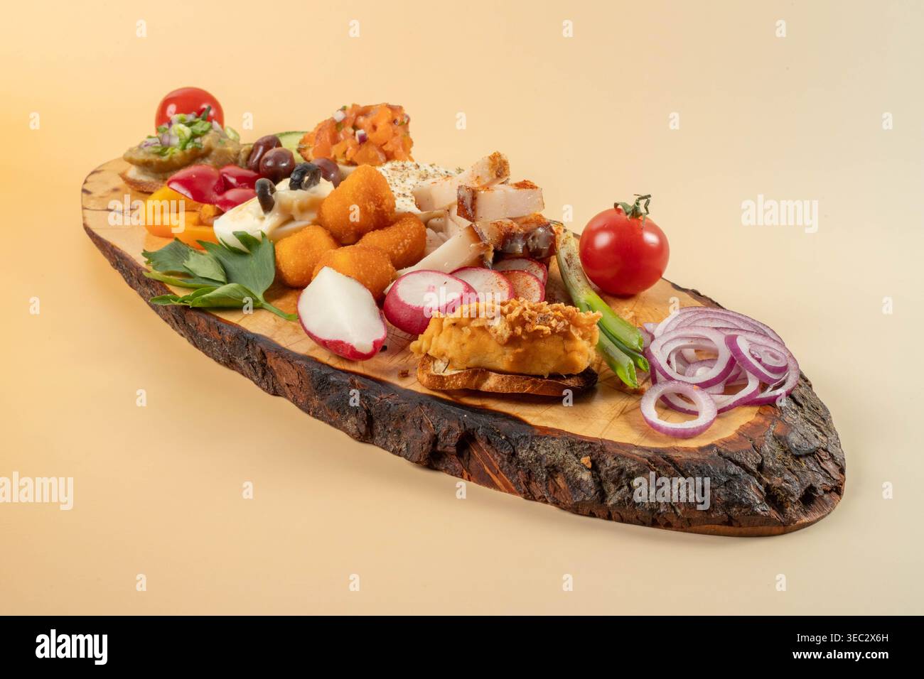 Piatto tradizionale rumeno di antipasti con grasso di maiale, polpette di formaggio fritte e verdure fresche su un rustico asse di legno su sfondo di pesca. Foto Stock