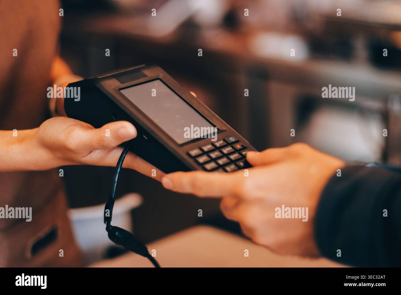 Barista asiatica anziana che riceve pagamenti mobili da un cliente tramite smartphone presso un bar che dimostra una moderna transazione senza contanti in un ambiente accogliente Foto Stock