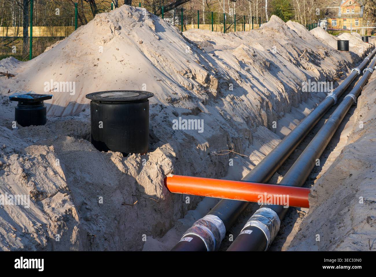 Tubi per utenze interrati isolati installati in trincee durante i lavori di costruzione delle infrastrutture Foto Stock