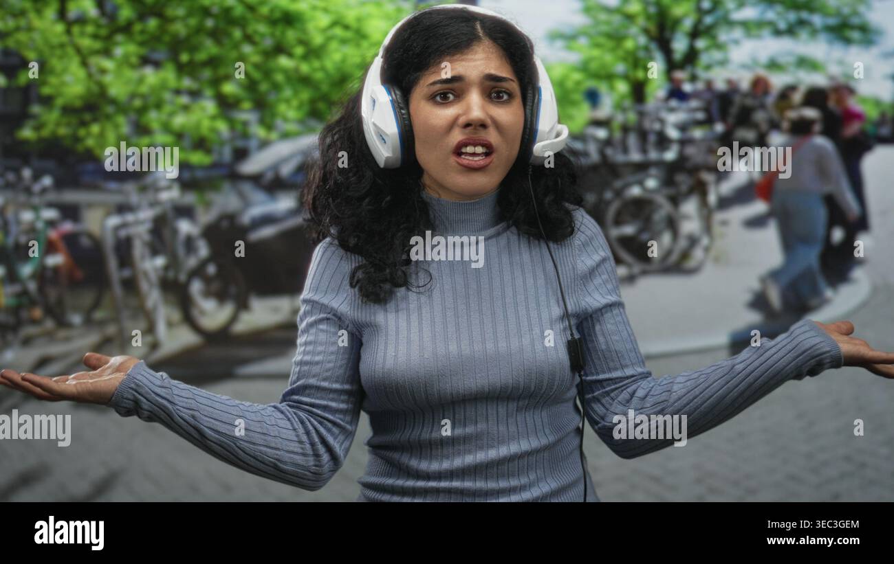 Giovane donna araba con lacrime e braccia incrociate sulla strada che indossa cuffie, che soffre di forte rumore; isolamento frustrante. Foto Stock