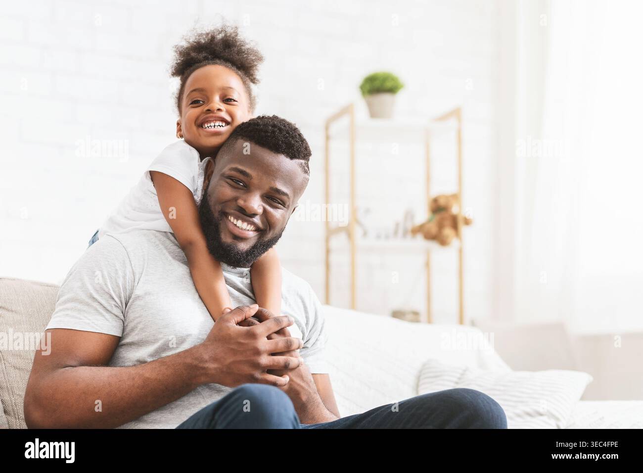 Padre e figlia sorridenti che si godono momenti di qualità insieme a casa in una giornata di sole Foto Stock
